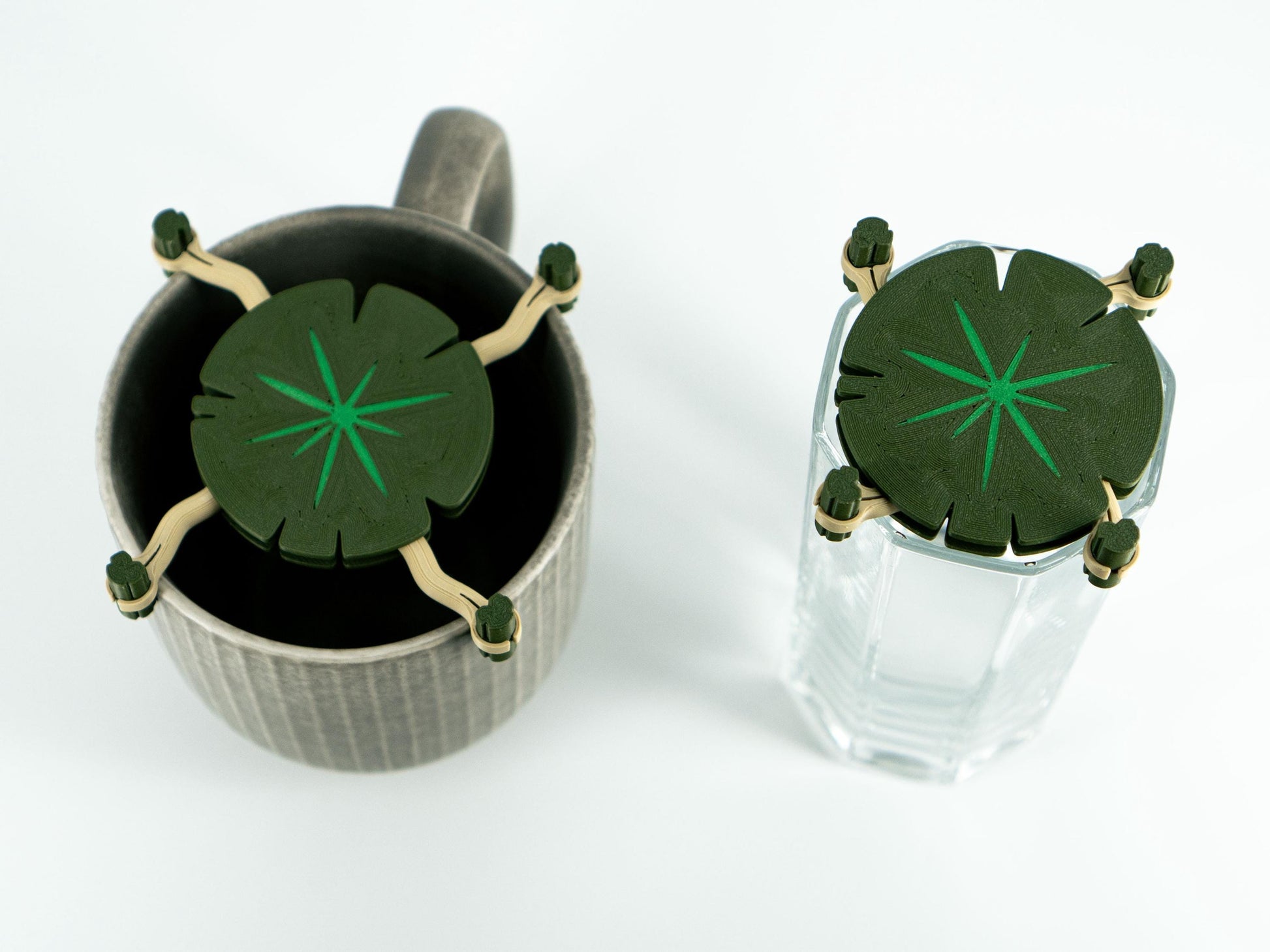 Two glass containers with green leaf-shaped lids on a white background