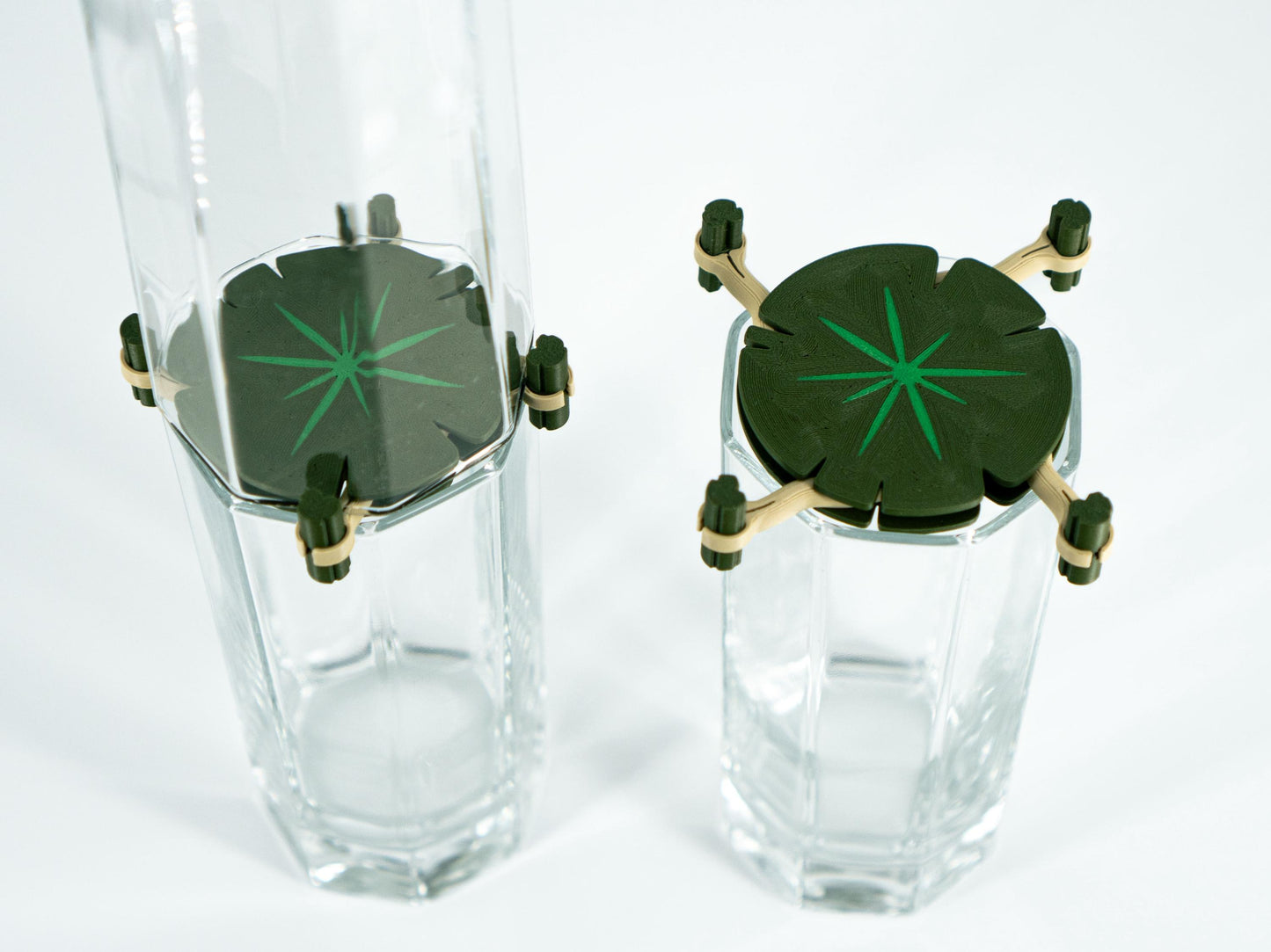 Two clear glass tumblers with green starburst designs on a white background
