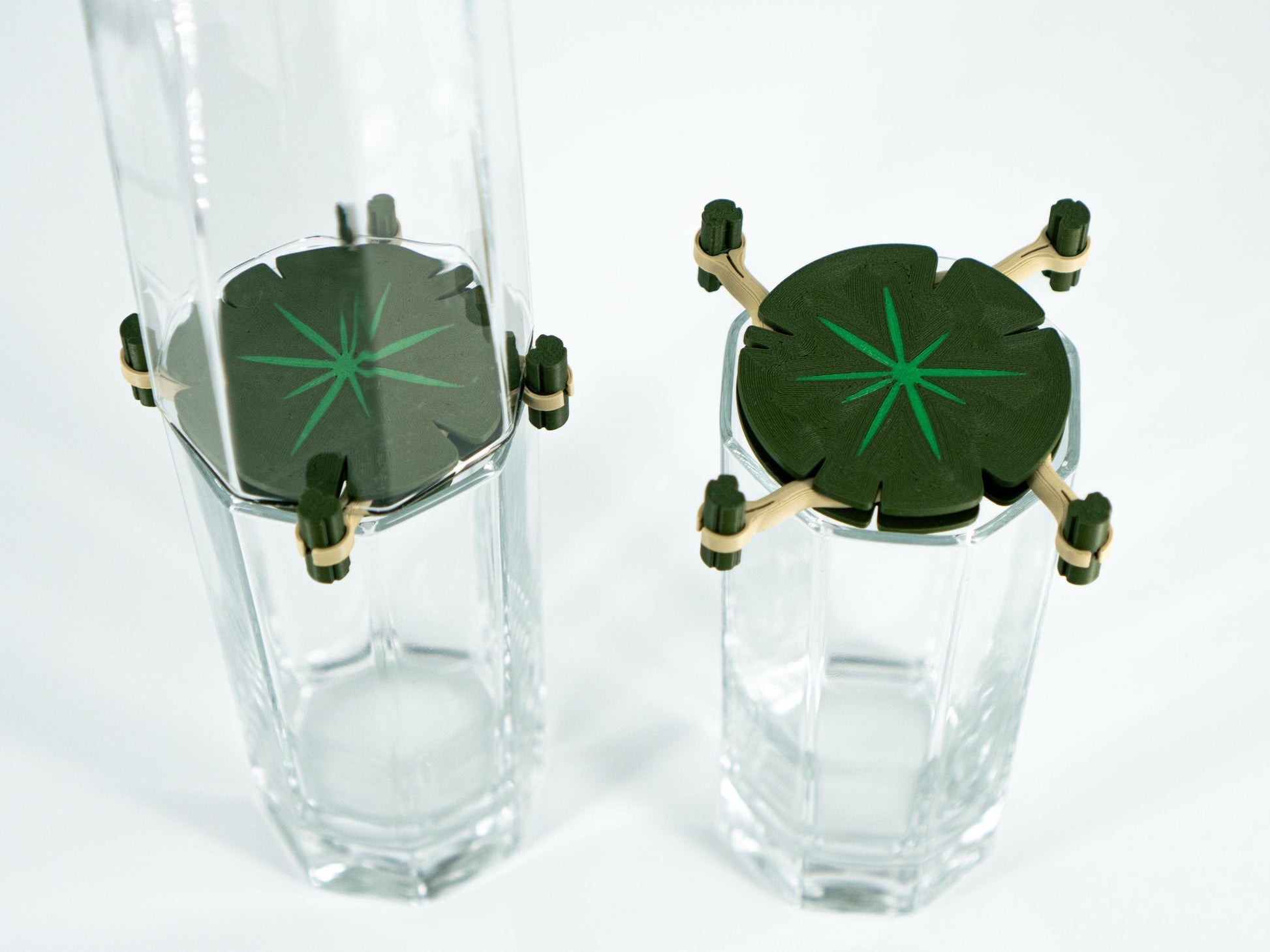 Two clear glass tumblers with green starburst designs on a white background