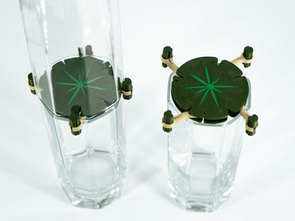 Two clear glass tumblers with green starburst designs on a white background