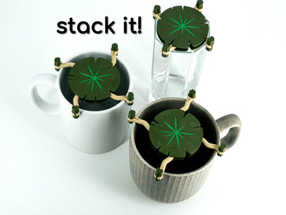 Three mugs with green leaf-shaped coasters on a white background, with text 'stack it!' above.