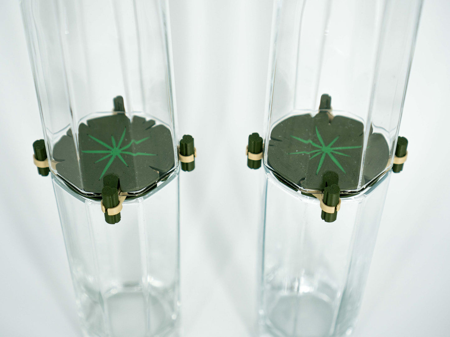 Two clear glass tumblers with black bases and green star designs on a white background